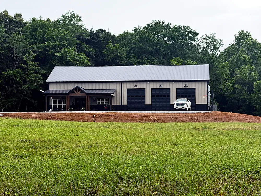Custom barndominium with three garage bays and covered porch in rural Western Kentucky