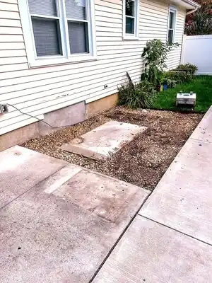 Side yard with gravel, concrete slabs, and plants; exterior remodel prep in Murray KY