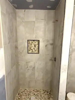 Custom tiled shower with pebble floor and marble walls