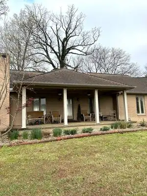 Completed brick house with a covered back porch supported by white columns, seating, and ceiling fans in Murray, KY.