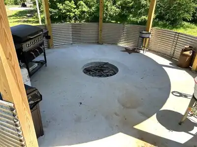 {
  "description": "The image shows a completed outdoor living area featuring a circular poured-concrete patio with a central