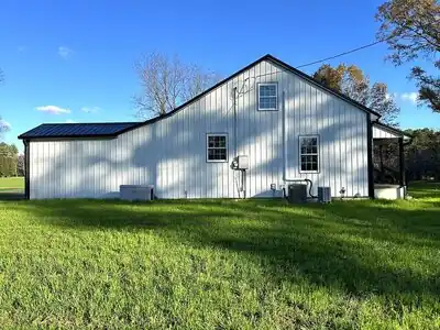 Metal-clad shop building on a grassy field under a blue sky; Murray, KY