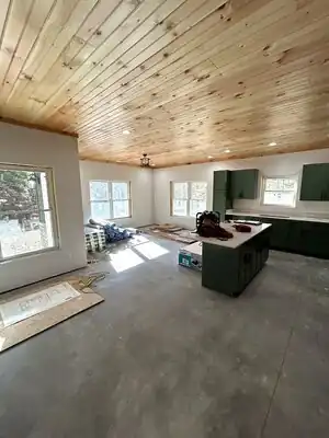 In-progress kitchen with green cabinets, wood ceiling, and central island.