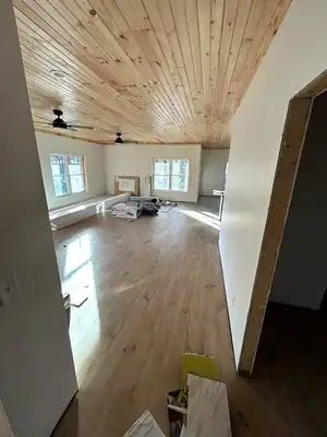 Interior room under construction with wood-paneled ceiling, light flooring and construction materials