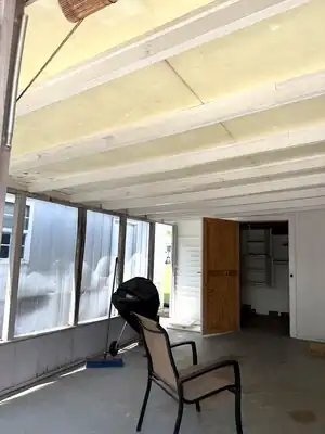{
  "description": "The image shows an interior covered porch or sunroom that is in the middle of a remodel. The ceiling feat