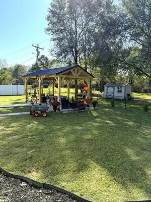 Completed wooden backyard pavilion with metal roof and seating in a Kentucky yard