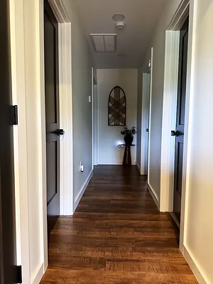 Finished interior hallway with dark doors, white trim, and wood-look flooring in Murray KY
