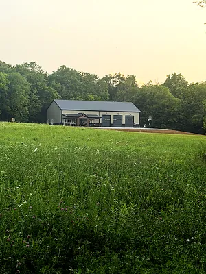 Barndominium and shop at sunset across a wildflower field in rural Kentucky