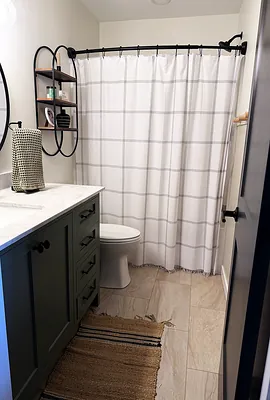 Finished guest bathroom with green vanity, marble-look counter, and tile floor in Murray KY
